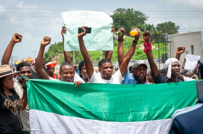 Protesters in the EndSARS Protest of 2020 walking behind the Nigerian flag